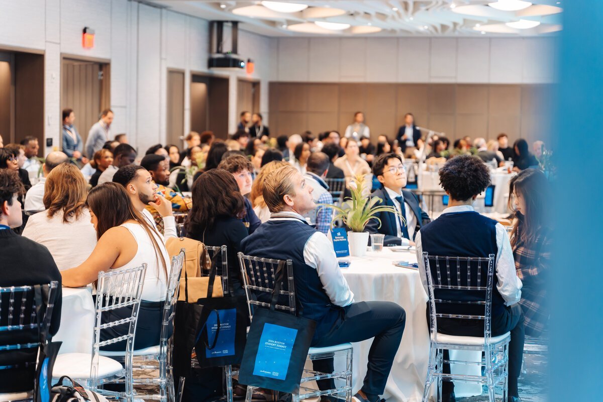 Students and professionals seated at round tables during a summit