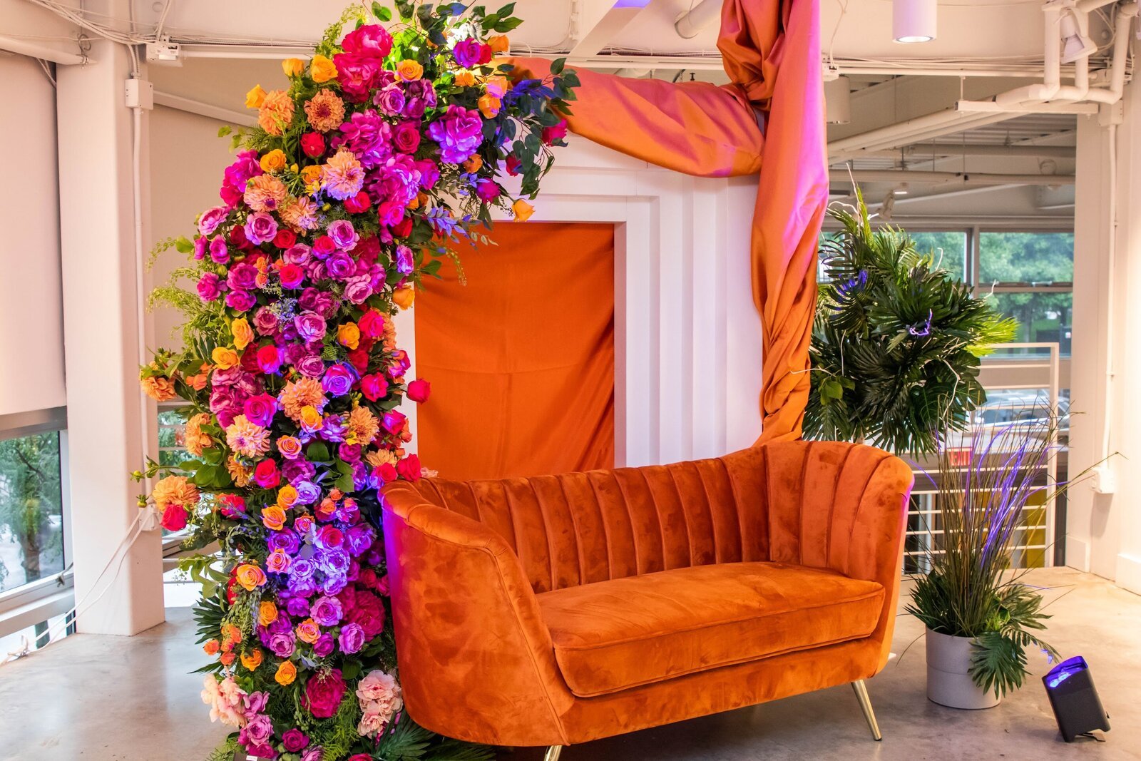 Floral installation with an orange velvet sofa