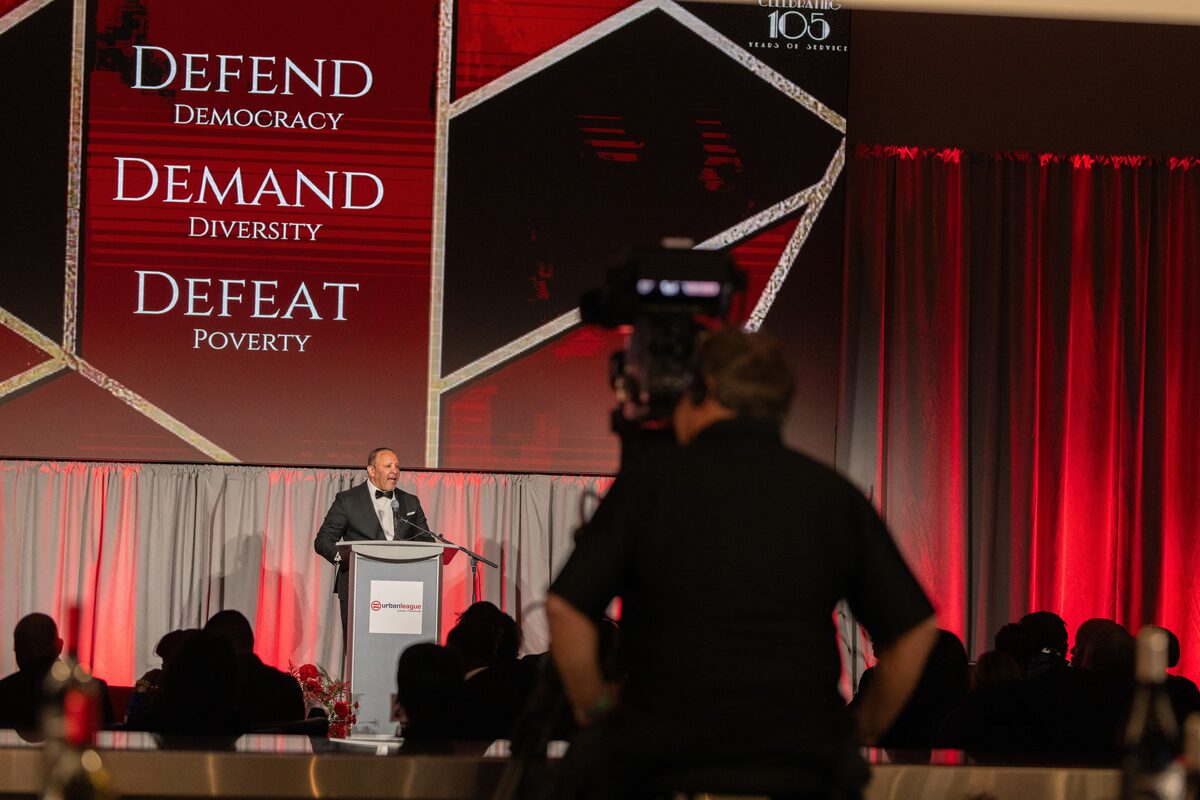 Speaker at the Urban League gala podium under red lighting